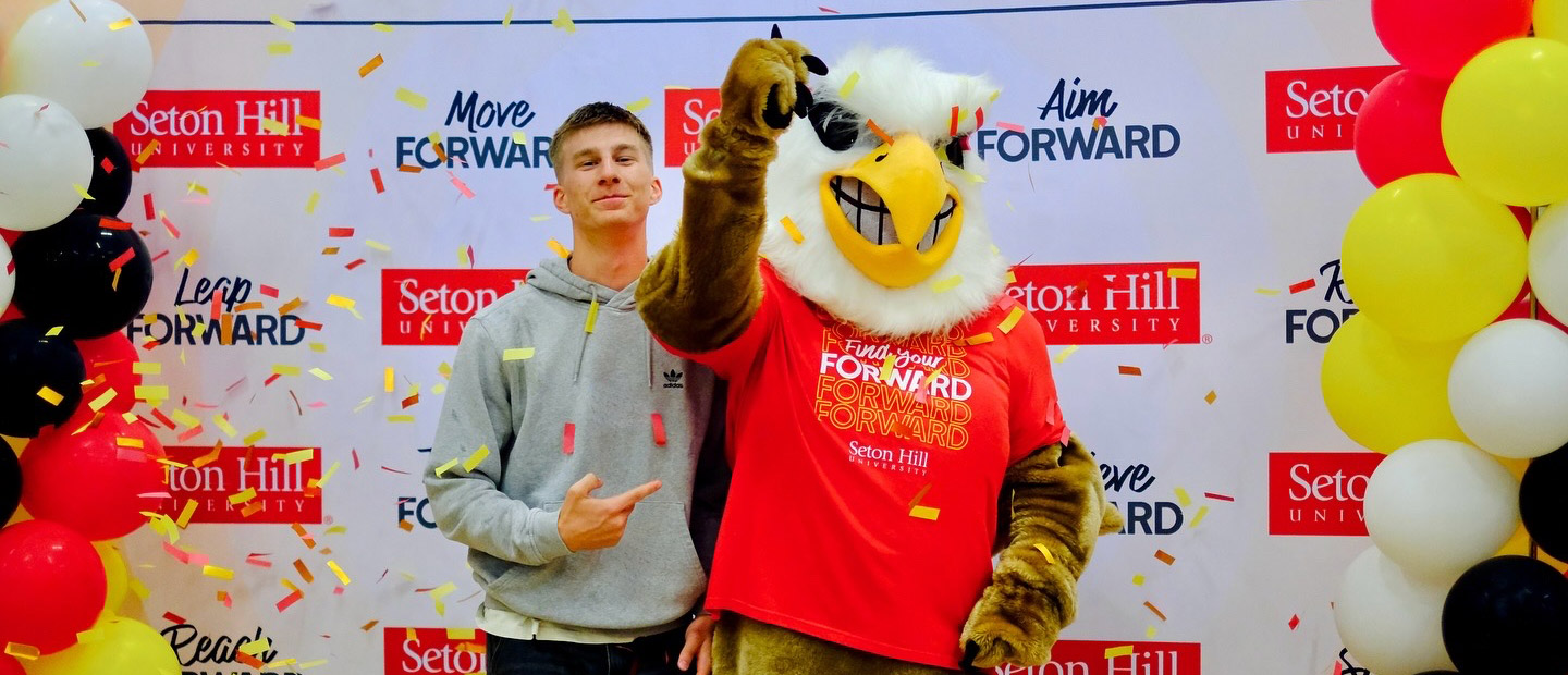 A student at accepted students day poses with the griffin mascot