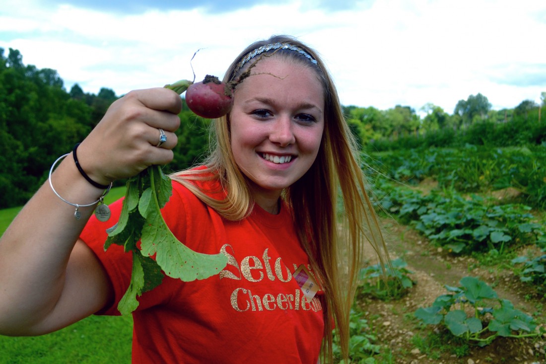 A student holding up a freshly picked radish. 